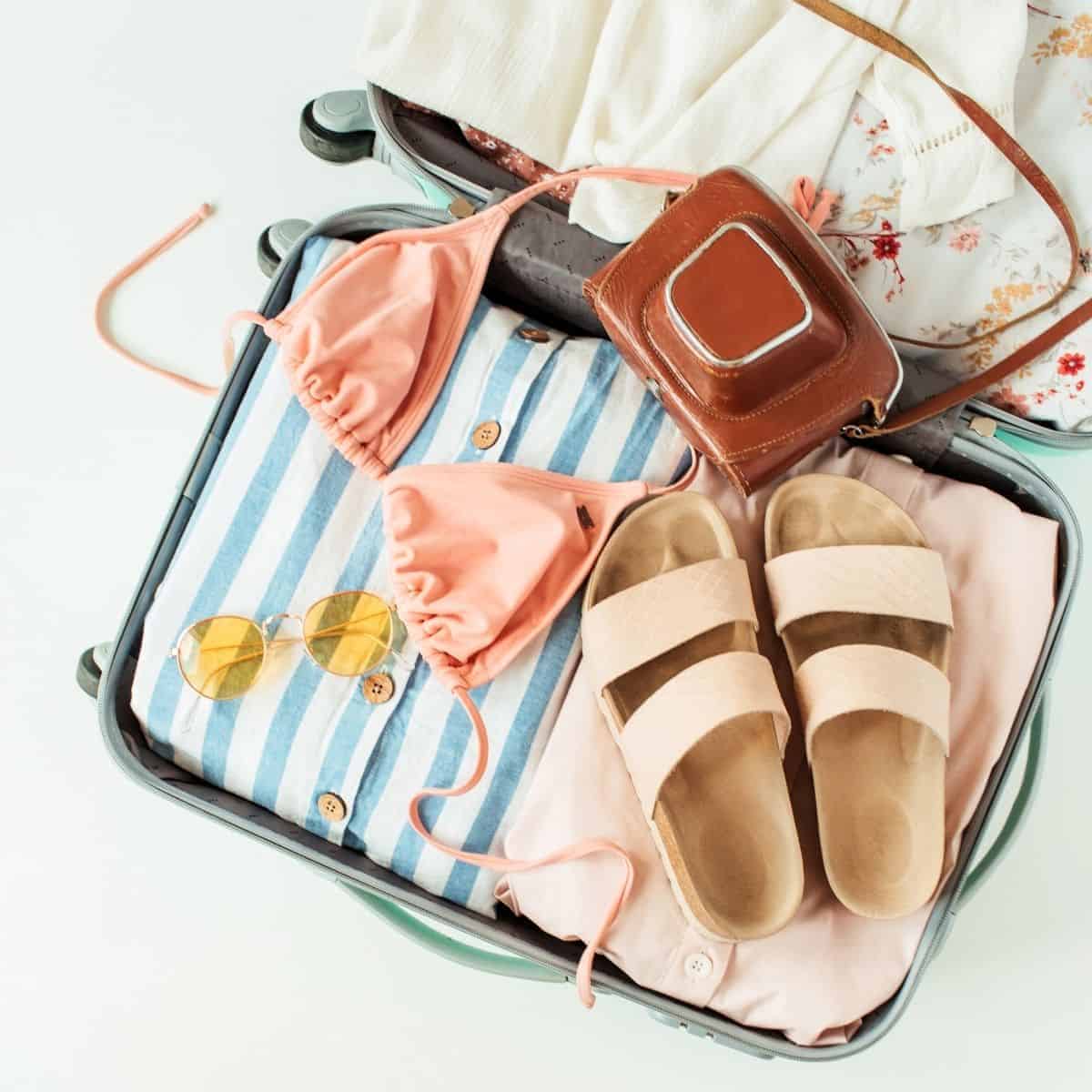 bag sunglasses sandals shown as traveling essentials for women.