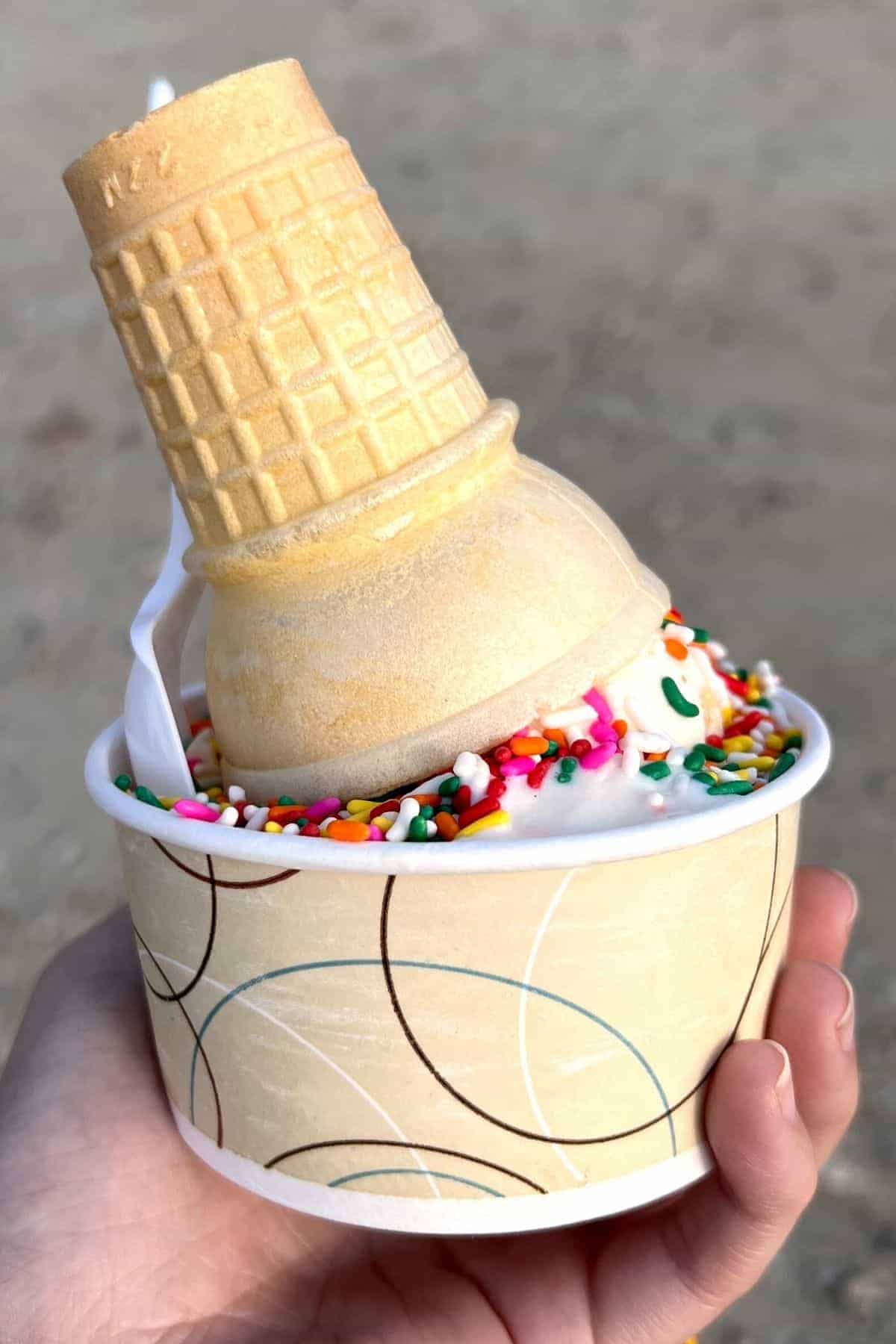 ice cream in a cup with a cone on top.
