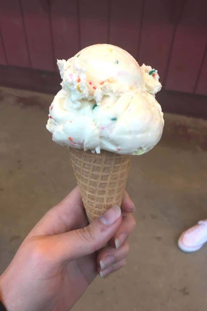 scoop of birthday cake ice cream on a sugar cone.