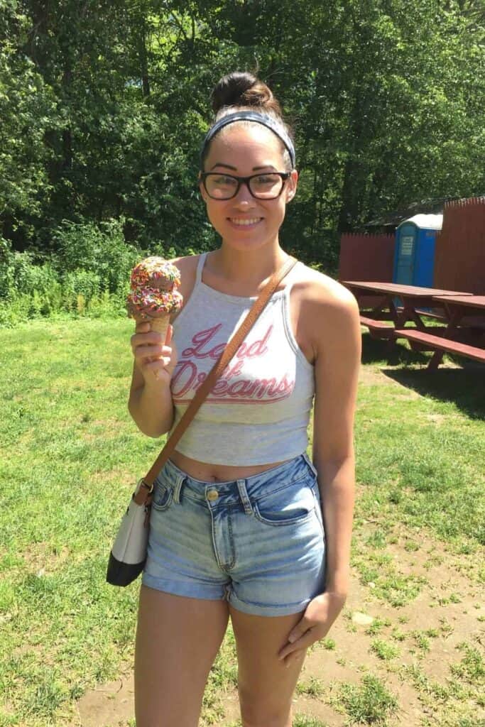 kailey holding an ice cream cone with chocolate ice cream and sprinkles.