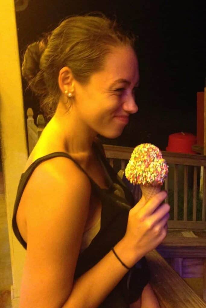 kailey holding ice cream cone with a scoop on it at night.