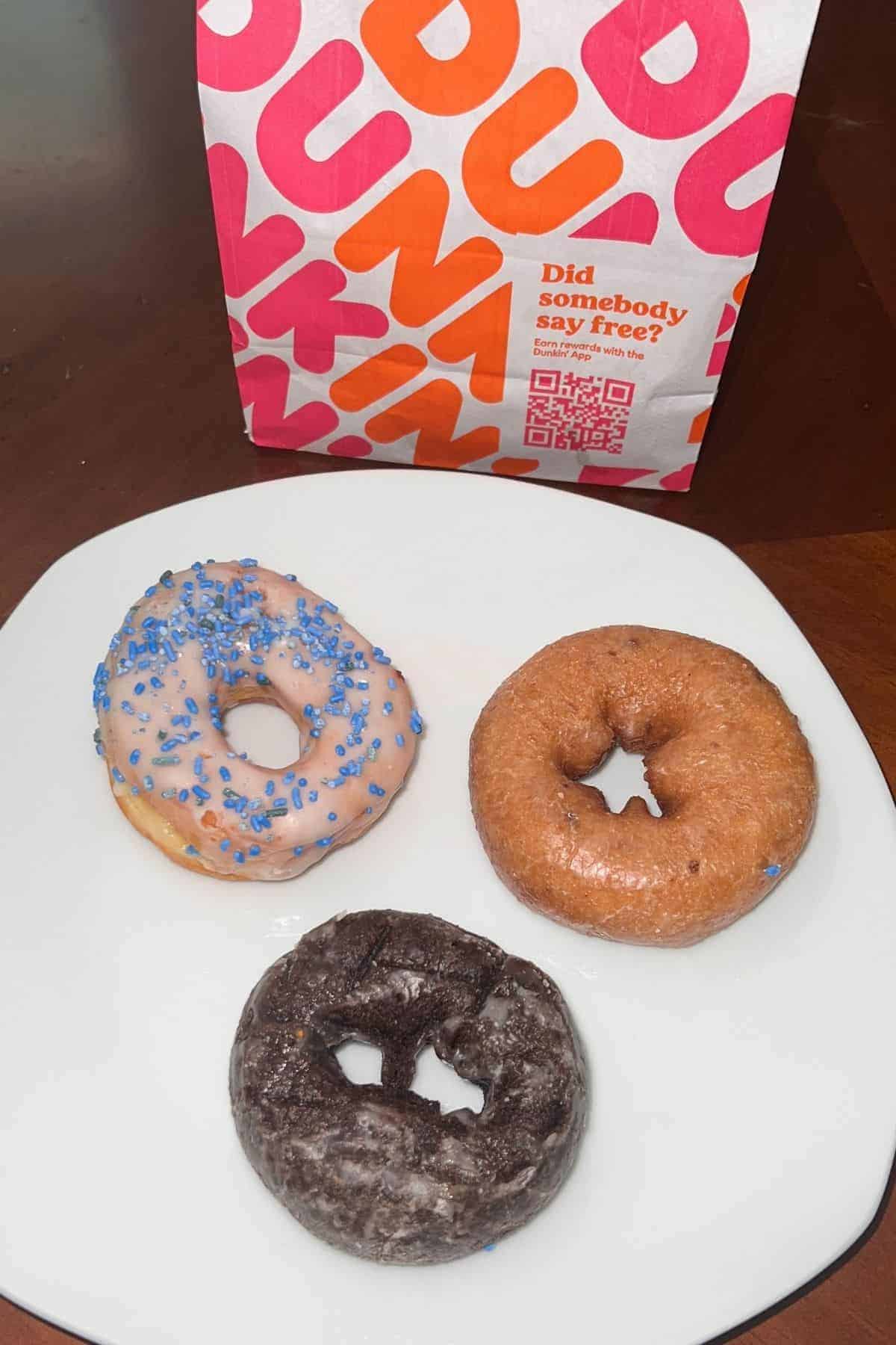 dunkin donuts on a plate with dunkin bag in the background.