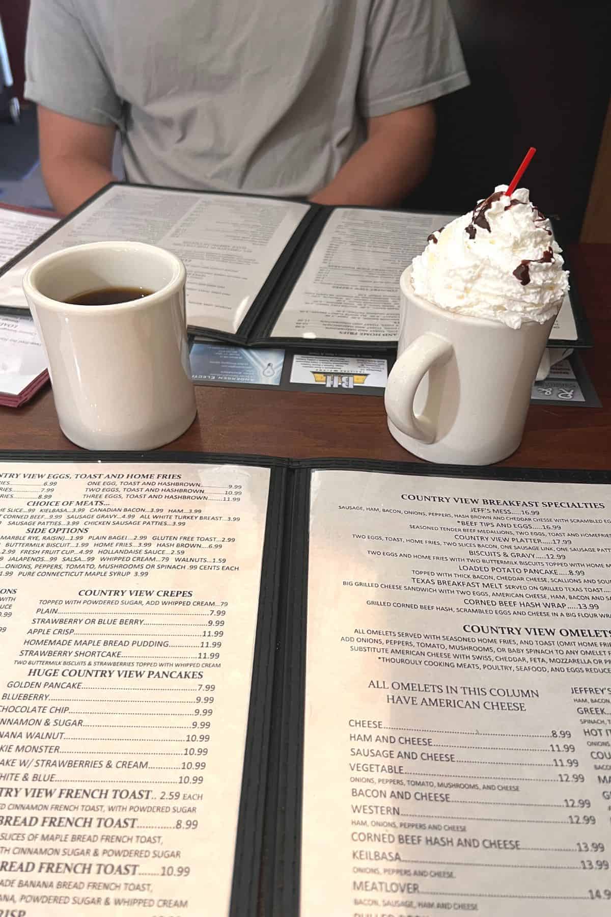 menus, coffee, and a hot chocolate on a table at country view restaurant.