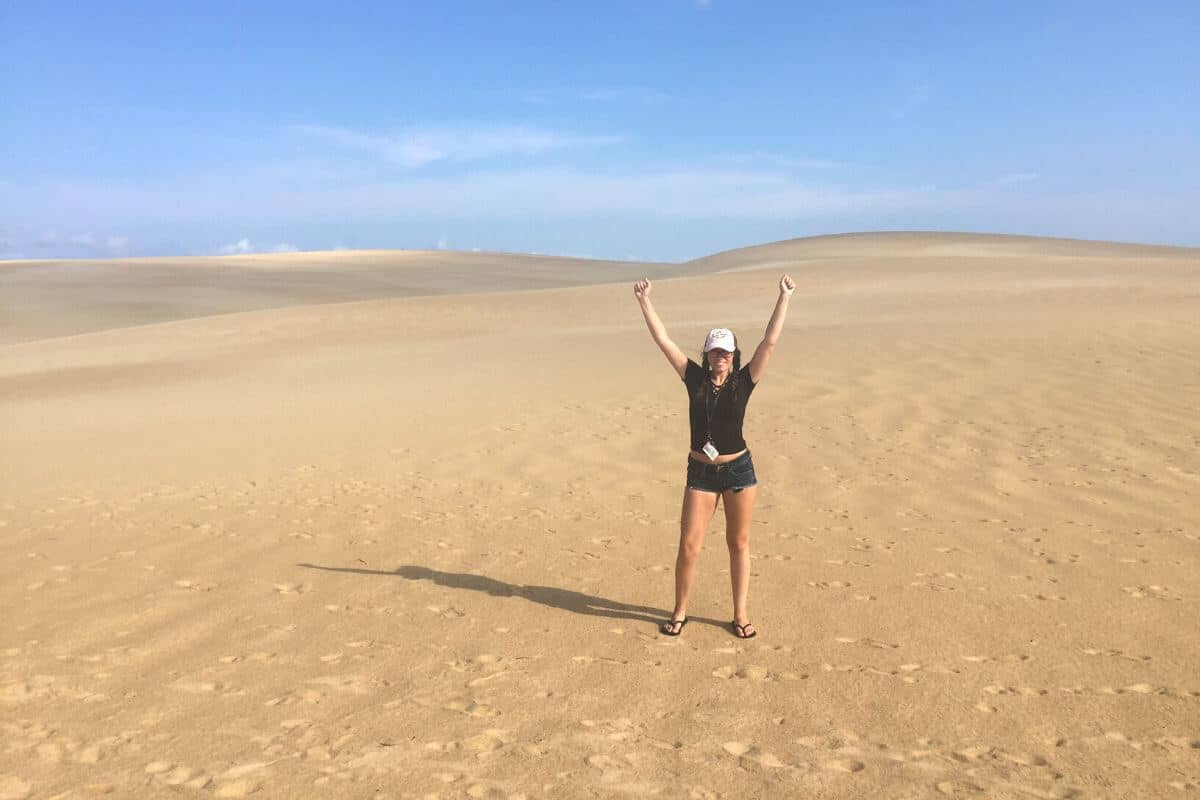 girl standing among sand dunes at jockeys ridge state park.