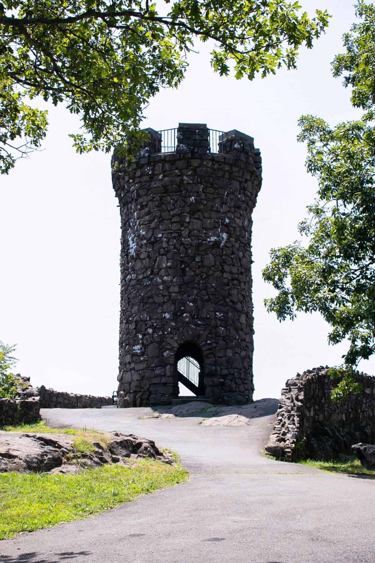 A stone tower in the middle of a grassy field.
