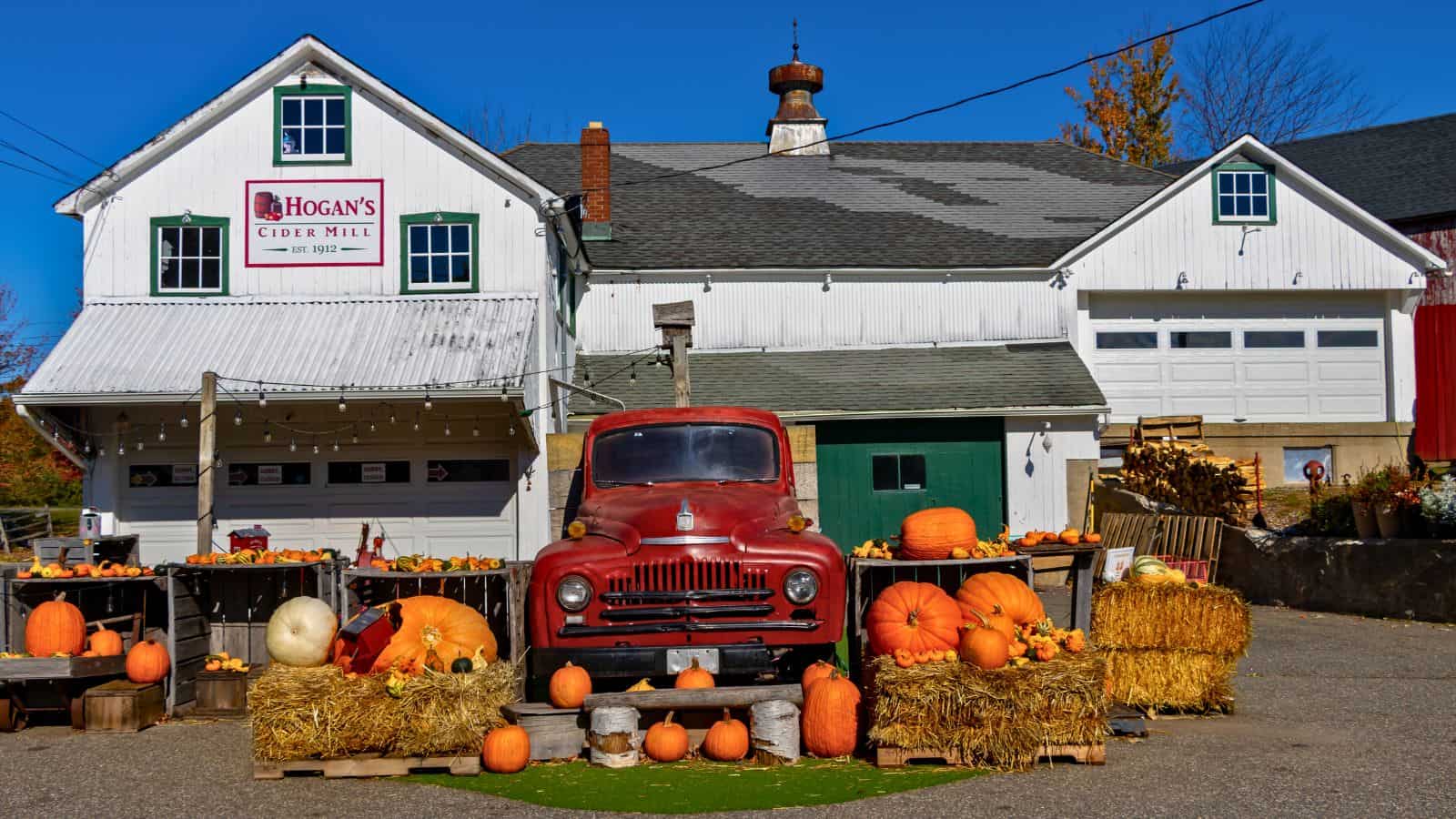 A vintage red truck parked in front of Hogan’s Cider Mill, surrounded by pumpkins and hay bales, a classic Connecticut thing to do in fall.