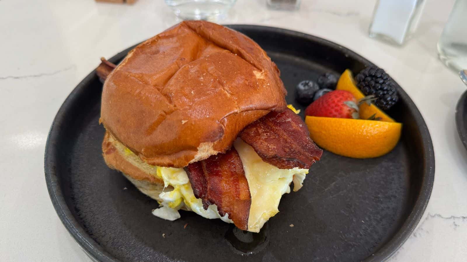 Start your day right in Niantic, CT with a savory breakfast sandwich—bacon, egg, and cheese on a bun—served with fresh fruit. Fuel up before exploring all the things to do in Niantic CT!.