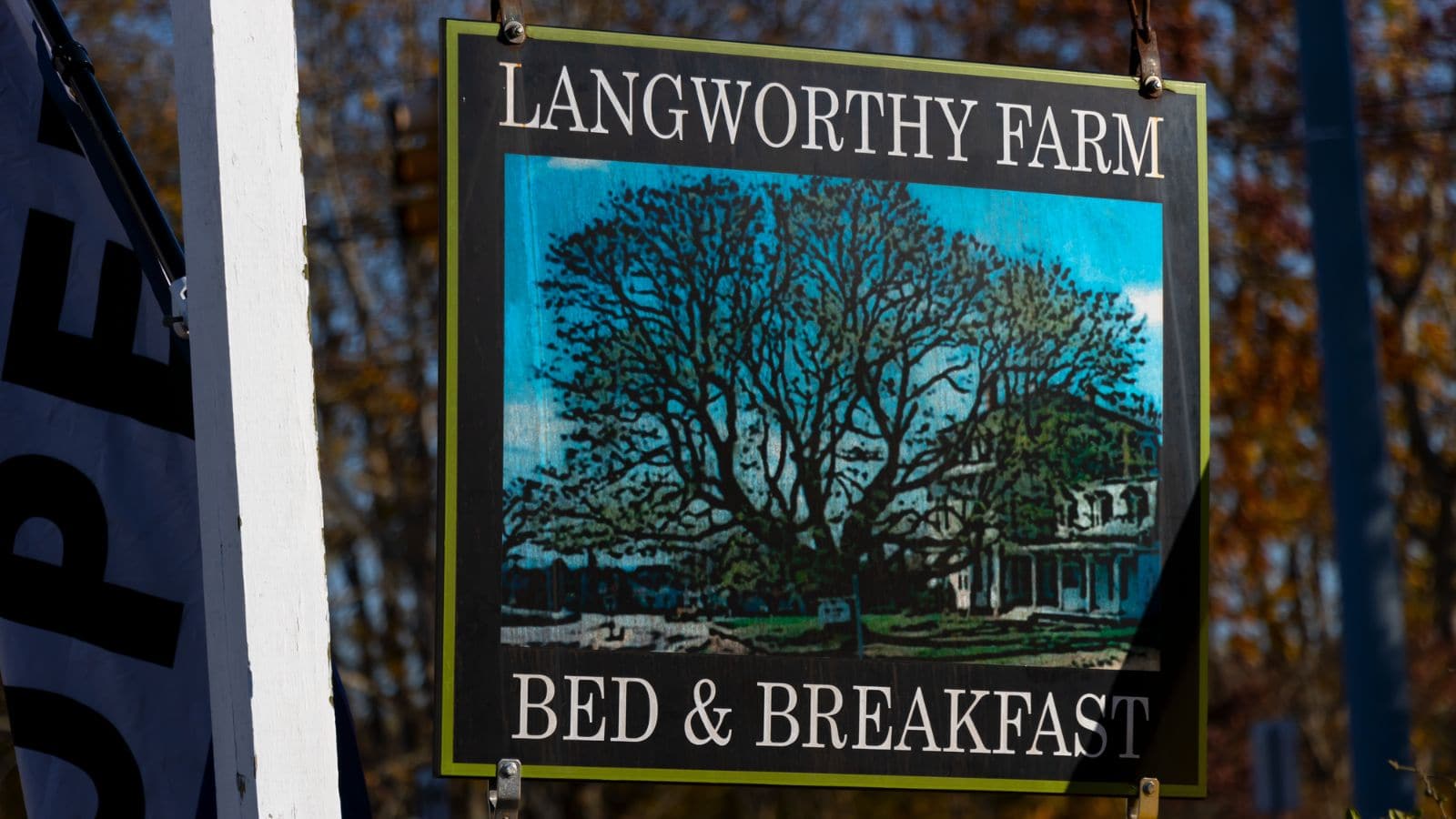 A sign for Langworthy Farm Bed & Breakfast hangs outdoors, featuring an illustration of a large tree and a house.