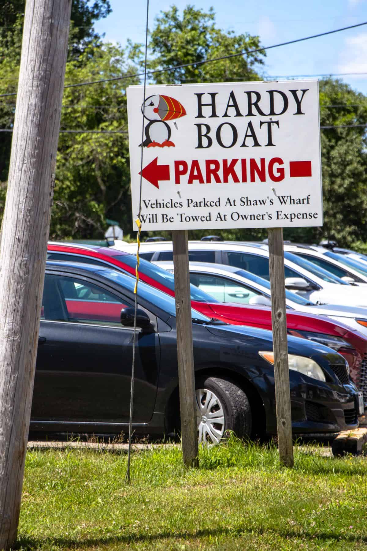 A sign reads "Hardy Boat Parking" with a red arrow pointing left; several parked cars and greenery are visible in the background.