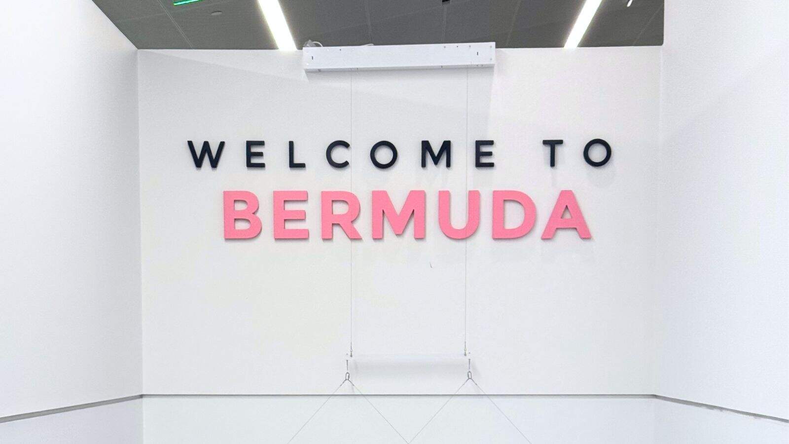 A white wall with the words "WELCOME TO BERMUDA" in large black and pink letters.