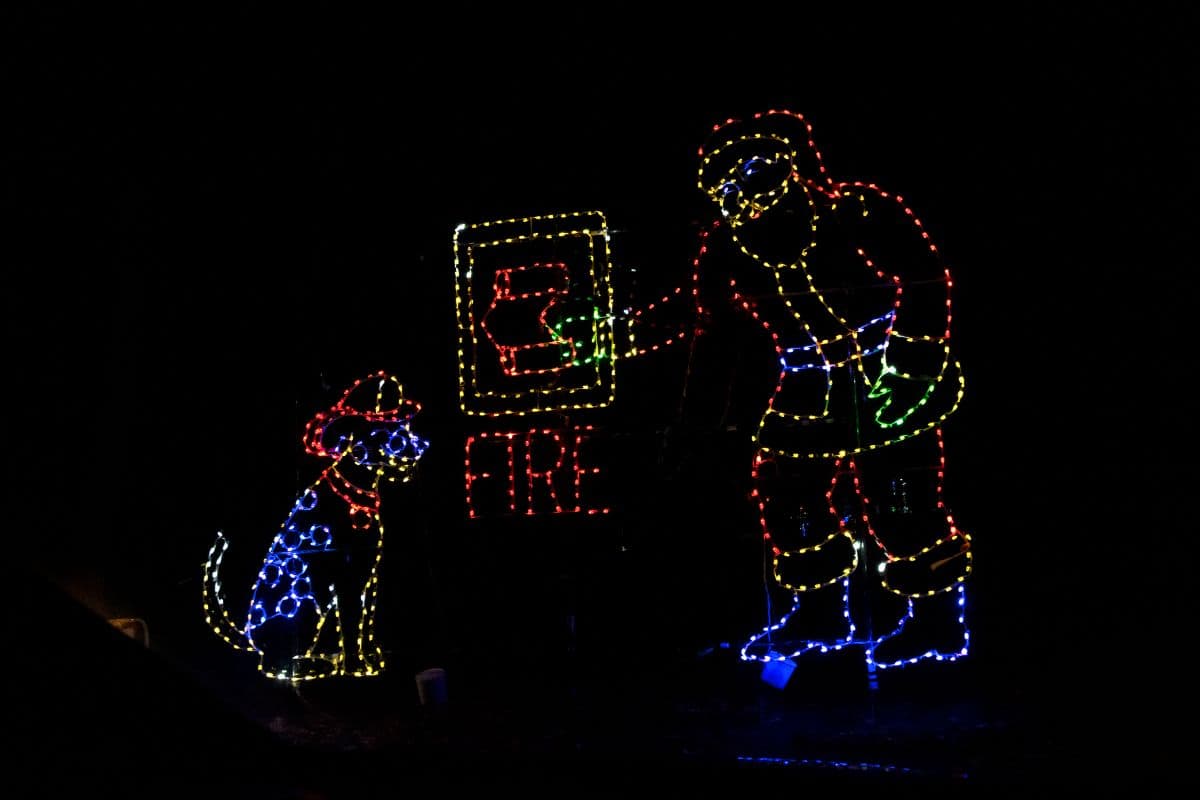 A light display shows a dog in a firefighter hat and a figure in winter clothes pressing a fire alarm button with the word "FIRE" illuminated below.