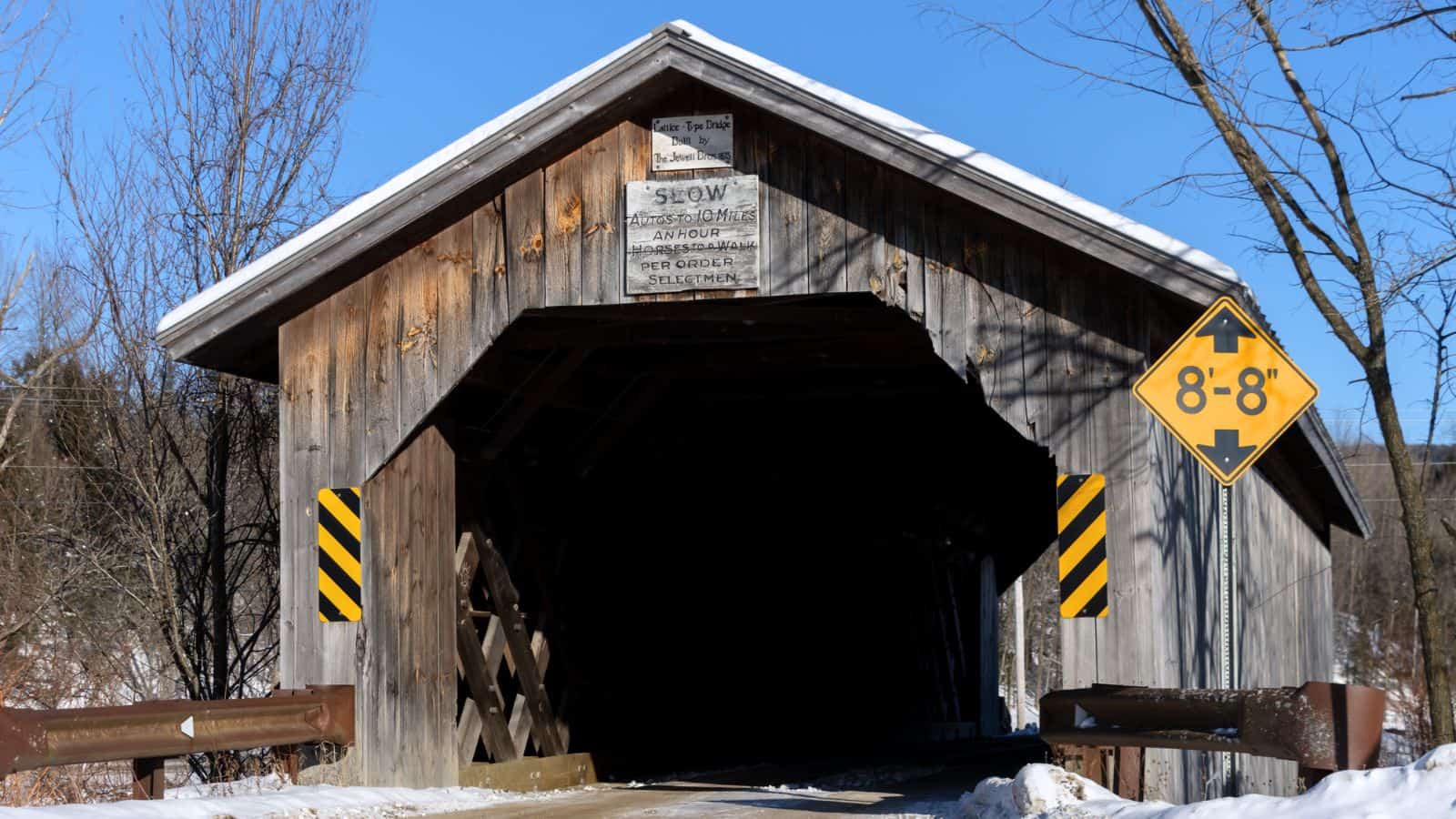 A classic wooden covered bridge with a sign, reminiscent of the charming New England covered bridges.