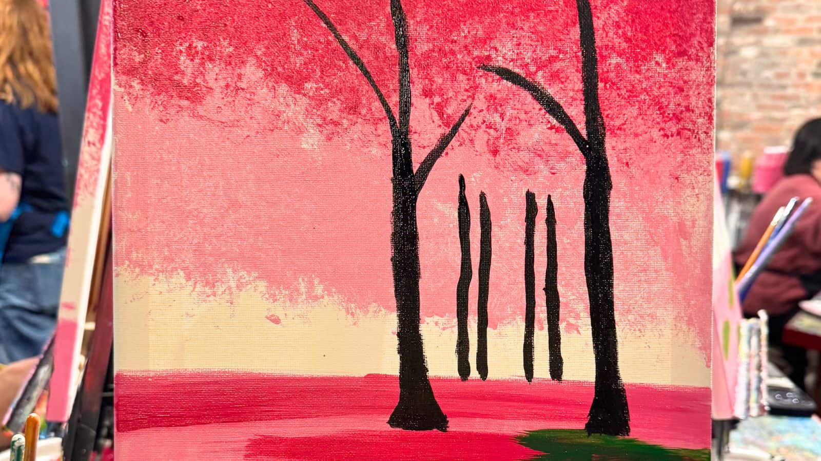 A painting depicting black tree silhouettes on a pink and red background with more trees in the distance.