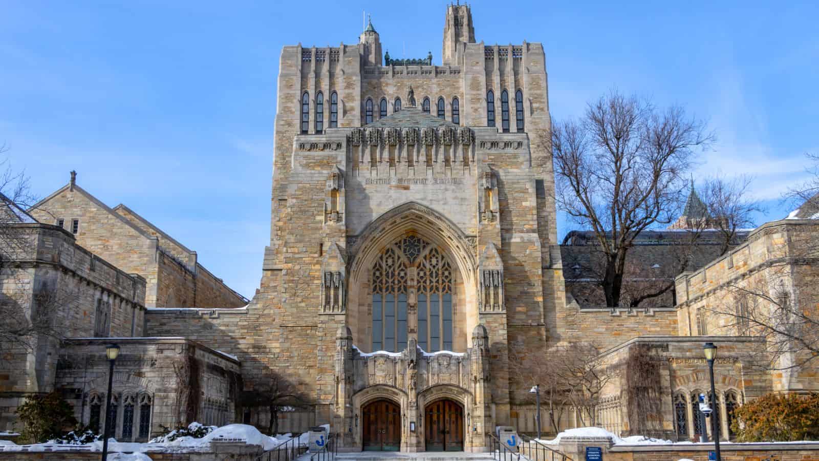 A large, stone Gothic-style building with tall arched windows and decorative carvings, surrounded by snow and leafless trees.