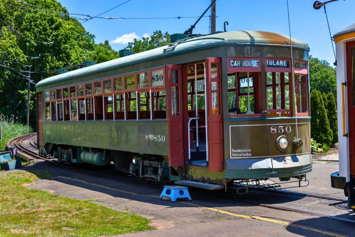 A vintage green streetcar numbered 850 is parked on curved tracks outdoors, with signs reading "CAR HOUSE" and "TULANE" above the front windows.