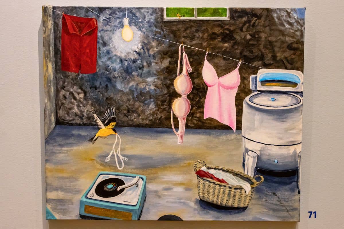A painting of laundry hanging on a line, a washing machine, a record player, a basket, and a bird holding socks in its beak in an indoor room.