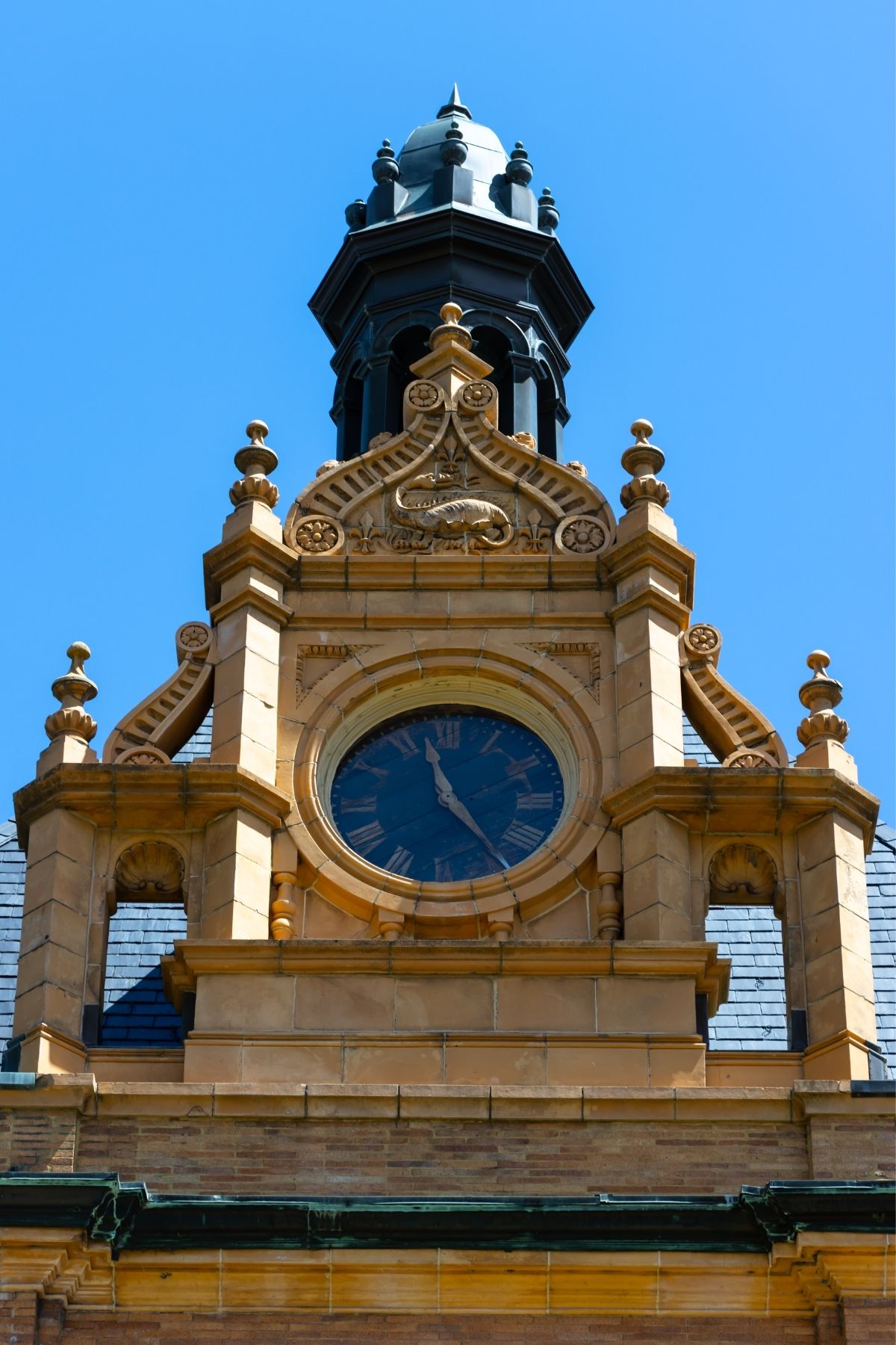 The ornate stone clock tower of a building featuring a golden relief of a dragon above the clock face.