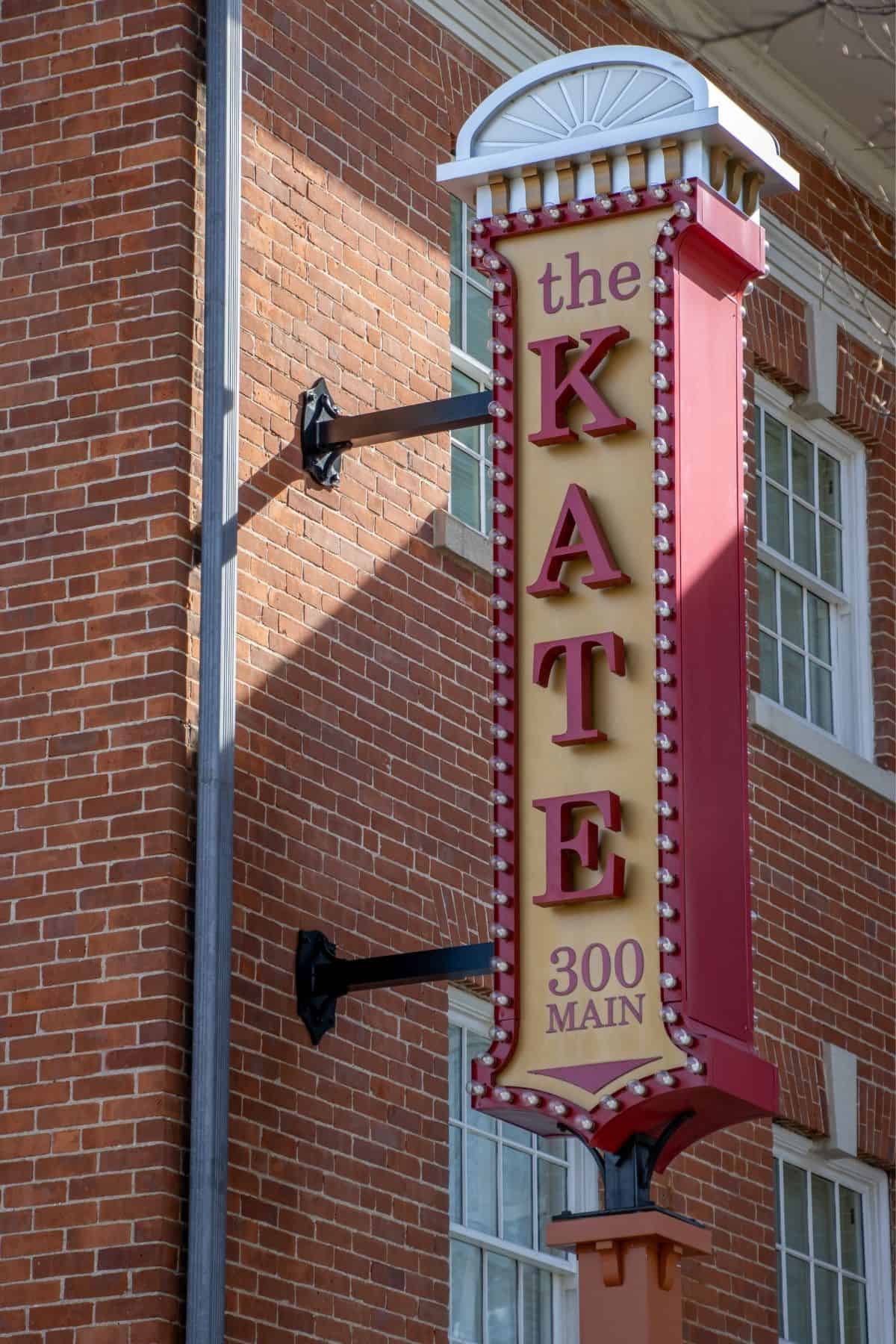 Vertical marquee sign on a brick building that reads “the KATE 300 MAIN” in red lettering.